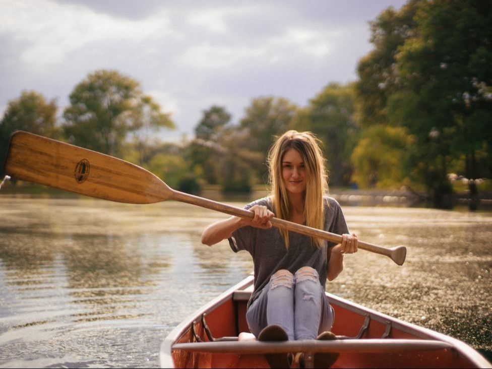 Woman in rowboat holding oar.